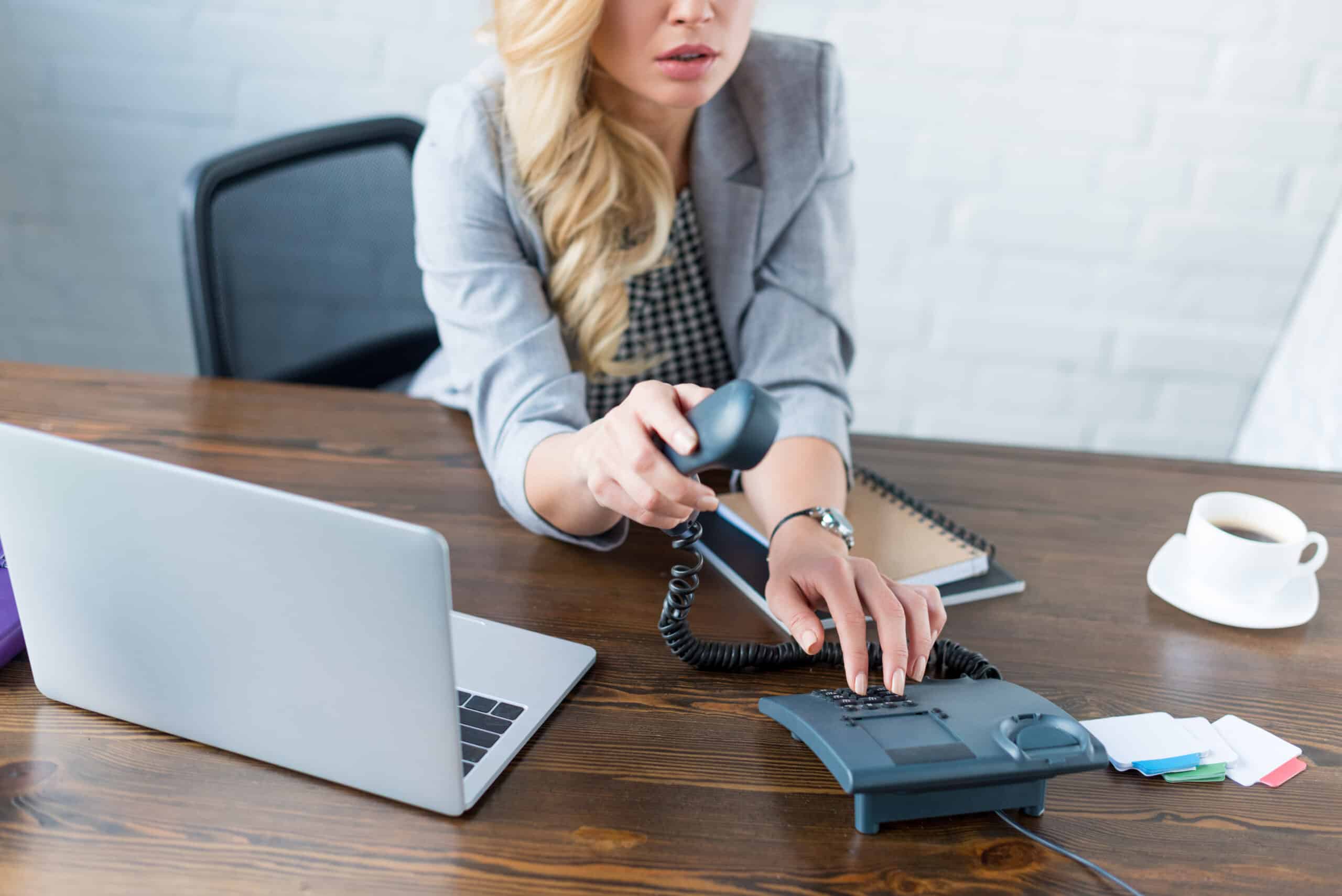 cropped image of businesswoman dialing number on stationary telephone
